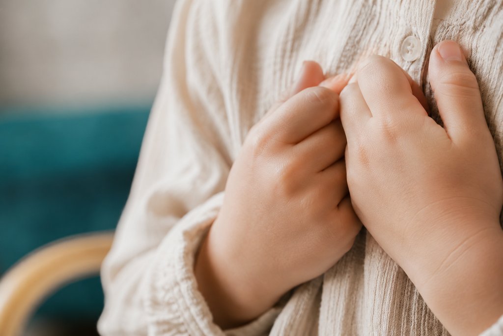 Mains d'un enfant posées l'une sur l'autre contre sa poitrine